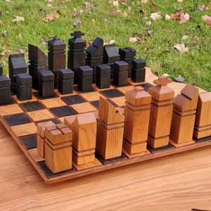 May include: A wooden chess set with black and brown pieces. The pieces are arranged on a black and white checkered board. The board is made of wood and has a natural finish.