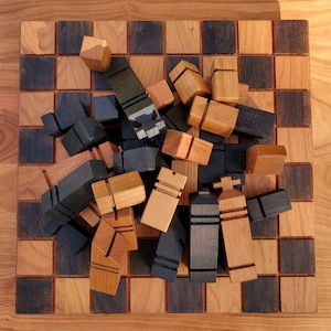 May include: A wooden chessboard with black and brown squares. The board is covered with wooden chess pieces in black and natural wood colors. The pieces are arranged in a random order.