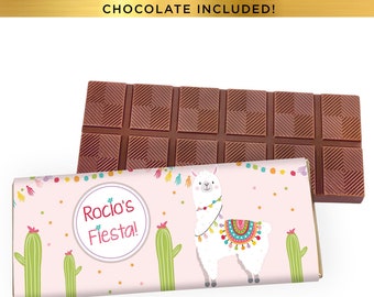 May include: A pink and white chocolate bar wrapper with a llama wearing a colorful blanket and a cactus on each side. The wrapper says "Rocio's Fiesta!"