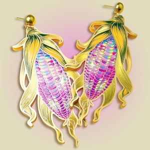 Pode incluir: Brincos em forma de espigas de milho. Os brincos apresentam um contorno dourado com desenhos detalhados de folhas e grãos de milho. Os grãos são uma mistura de rosa, roxo e cores iridescentes, enquanto as folhas são amarelas e verdes.