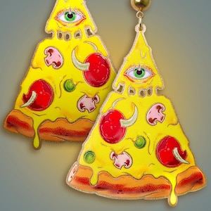 Könnte beinhalten: Ein Paar ausgefallene Ohrringe in Form von Pizzastücken. Jedes gelbe Stück hat rote Tomaten, grüne Paprika und Pilzbelag. Die Oberseite jedes Stücks hat eine dreieckige Form mit einem Augendesign. Die Ohrringe haben einen goldfarbenen Stecker.