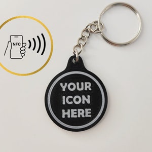 May include: Black round keychain with a white circle and the text "YOUR ICON HERE" in the center. The keychain has a silver metal ring.