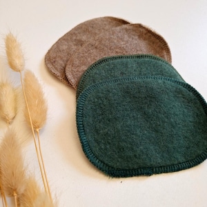 Könnte beinhalten: Drei wiederverwendbare Abschminkpads. Zwei sind braun und eines ist grün. Die Pads sind oval geformt und haben einen genähten Rand.