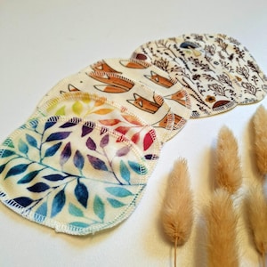 Könnte beinhalten: Ein Set mit sechs wiederverwendbaren Abschminkpads mit verschiedenen Mustern. Die Pads bestehen aus weichem, saugfähigem Stoff und sind so konzipiert, dass sie sanft zur Haut sind. Die Muster umfassen einen Regenbogen an Farben, ein Fuchsdesign und ein Blumendesign.