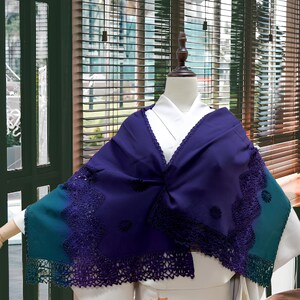 May include: A purple and teal shawl with a crocheted lace trim. The shawl is draped over a white kimono with a floral pattern.
