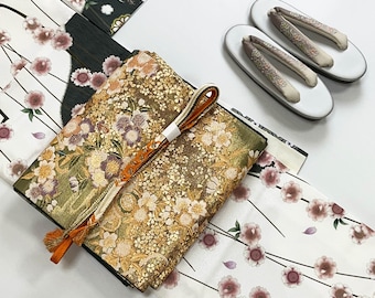 May include: A set of traditional Japanese clothing items, including a white kimono with a floral pattern, a gold and green kimono with a floral pattern, and a pair of white sandals with floral embroidery.