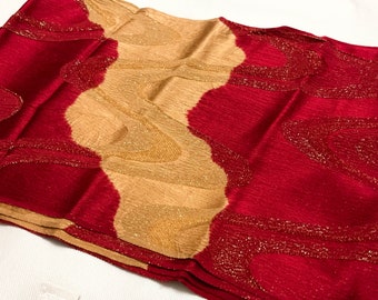 May include: A red and gold fabric scarf with a swirling pattern. The fabric has a subtle shimmer.