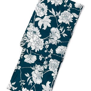 May include: A folded, dark teal fabric with a white floral pattern. The design features large, stylized peony blooms and leaves. The fabric is likely used for clothing or home decor.