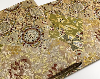 May include: A close-up of a fabric with a gold, green, and red floral pattern. The fabric is folded in half and has a textured surface.