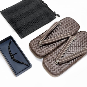 May include: A pair of brown geta sandals with woven texture and fabric straps, next to a black drawstring bag and a black beaded necklace in a blue box. The sandals are a traditional Japanese footwear.