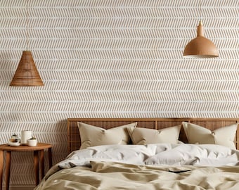 May include: A bedroom with a white wall featuring a brown geometric pattern wallpaper. The bed has a brown headboard and a white duvet with beige pillows. There are two hanging pendant lights with brown shades.