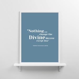 Op de afbeelding: Een ingelijst print met een blauwe achtergrond en witte tekst die luidt: "Niets kan het goddelijke decreet veranderen behalve dua" - Profeet Mohammed (vrede zij met hem).