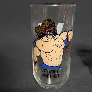 May include: A clear glass with a colorful illustration of a wrestler with the text "ULTIMATE WARRIOR" printed on the bottom.