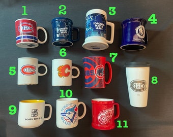 May include: A collection of 11 ceramic mugs featuring various hockey team logos, including the Toronto Maple Leafs, Montreal Canadiens, Chicago Blackhawks, and Boston Bruins. The mugs are in various colours, including white, blue, red, and yellow.