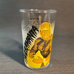 May include: A clear glass with a yellow and black image of Hulk Hogan, a professional wrestler, with the text "Hulk Hogan" on the glass.