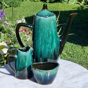 Puede incluir: Un juego de té de cerámica verde y marrón con tetera, jarra de crema y azucarero. El juego tiene un acabado de esmalte de goteo.