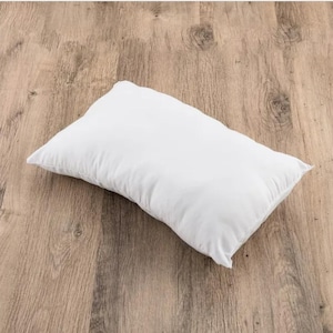 Puede incluir: Una almohada blanca sobre una superficie de madera.