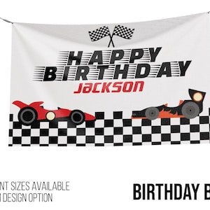 May include: White birthday banner with the text "HAPPY BIRTHDAY JACKSON" in black and red. Features two race cars and checkered flags. The banner is designed for a birthday celebration.