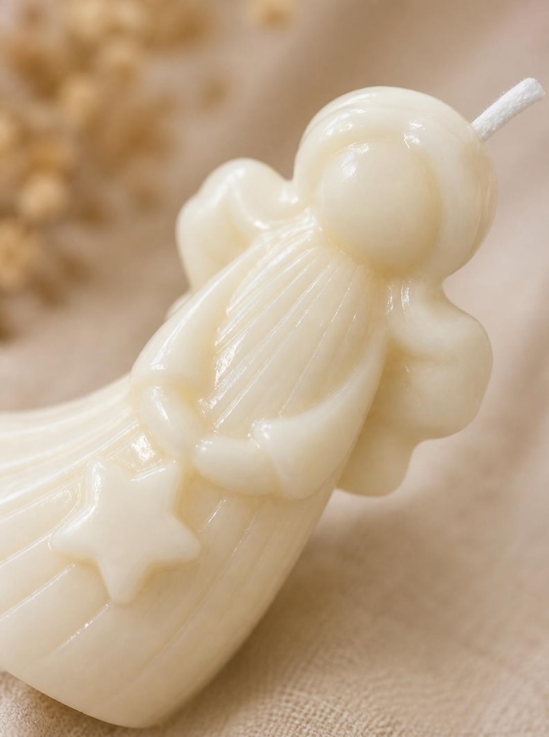 K&ouml;nnte beinhalten: Eine cremefarbene Wachskerze in Form einer stilisierten Figur mit rundem Kopf, flie&szlig;endem Gewand und Fl&uuml;geln. Die Figur h&auml;lt einen f&uuml;nfzackigen Stern in den H&auml;nden, und ein wei&szlig;er Baumwolldocht ragt oben aus dem Kopf der Kerze heraus.