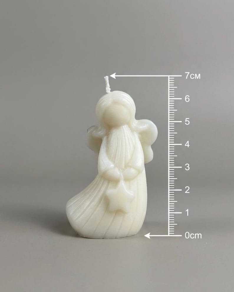 K&ouml;nnte beinhalten: Eine cremewei&szlig;e, engelf&ouml;rmige Kerze mit einem Stern in den H&auml;nden und einem Docht an der Oberseite. Ein vertikales Lineal neben der Kerze zeigt eine H&ouml;he von etwa 7 cm an. Die Kerze hat eine glatte, geformte Oberfl&auml;che mit Fl&uuml;geln und einem flie&szlig;enden Gewand.