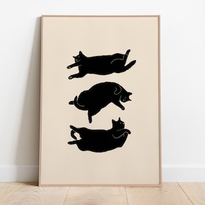 Può includere: Una stampa incorniciata beige con tre silhouette di gatti neri in diverse posizioni di sonno.