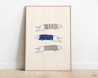 May include: A framed print with a minimalist illustration of three dachshunds wearing different patterned sweaters. The dachshunds are all facing right and are in a line, with the top dachshund wearing a striped sweater, the middle dachshund wearing a blue sweater with white dots, and the bottom dachshund wearing a striped sweater.