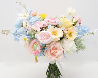 Könnte beinhalten: Ein lebendiger Blumenstrauß mit verschiedenen Blumen in Rosa, Gelb, Blau und Weiß. Der Strauß ist mit einem weißen Band gebunden und enthält Rosen und Gänseblümchen. Die Stiele sind grün.