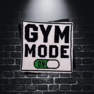 Op de afbeelding: Witte patch met zwarte tekst die "GYM MODE" zegt en een groene "ON" schakelaar.