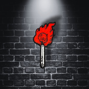 May include: Red and white embroidered patch of a skull on a stick with flames. The stick is black and the flames are red.