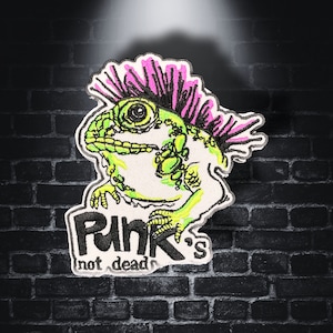 Könnte beinhalten: Grün-rosa gestickter Patch mit einem Cartoon-Eidechsen mit Irokesenschnitt und dem Text "Punk's not dead".