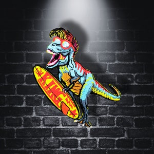 Può includere: Un dinosauro blu e verde con occhiali da sole sta cavalcando un surf giallo con la parola "KING" su di esso. Il dinosauro indossa un cappello rosso e giallo. Lo sfondo è un muro di mattoni scuro.