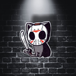 May include: A black cat wearing a white hockey mask with red accents and holding a silver knife. The cat is against a dark brick wall background.