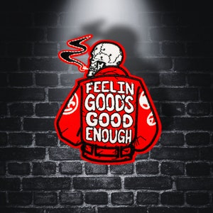 Può includere: Toppa ricamata rossa con uno scheletro che indossa una giacca rossa e fuma una sigaretta. La giacca ha il testo "Feelin Good's Good Enough" sul retro.