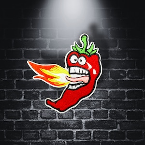 Può includere: Un peperoncino rosso con un viso da cartone animato e fiamme che escono dalla sua bocca. Il peperoncino è ricamato su uno sfondo nero.