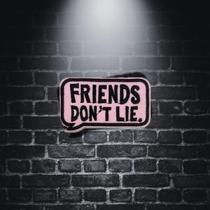 Può includere: Toppa ricamata rosa e nera con il testo "Friends Don't Lie."