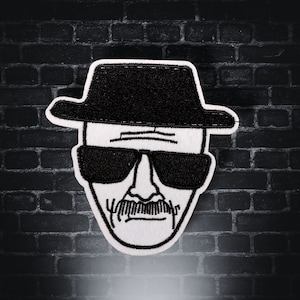 May include: Black and white embroidered patch of a man wearing a black hat and sunglasses. The man has a moustache and a serious expression.