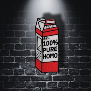 Könnte beinhalten: Ein roter und weißer Milchpaket-Patch mit dem Text "100% Pure Homo" auf der Vorderseite. Der Patch ist wahrscheinlich zum Annähen an Kleidung oder eine Tasche gedacht.