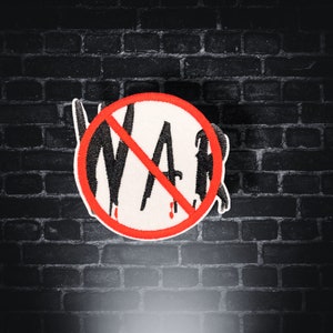May include: A red circle with a diagonal line through it, with the word "WAR" written in black letters inside. The circle is on a black brick wall background.