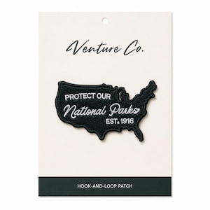 Può includere: Toppa ricamata nera a forma di Stati Uniti, con la scritta "PROTECT OUR National Parks EST. 1916" in bianco. La toppa è su una carta color crema con le parole "Venture Co." in alto.