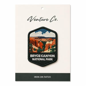 May include: Embroidered iron-on patch featuring a landscape of Bryce Canyon National Park. The patch has a black border and includes the text "Bryce Canyon National Park". The patch is on a white card with the text "Venture Co."