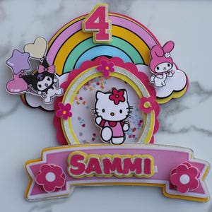 May include: A vibrant birthday cake topper with Hello Kitty, a rainbow, and the number 4. The topper includes the name "SAMMI" on a pink banner, with cartoon characters and floral accents. The design is colourful and playful, suitable for a child's celebration.