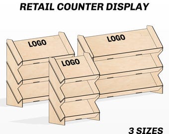 May include: Three wooden retail counter displays in different sizes. Each display has multiple shelves and a sloped top. The word "LOGO" is printed on each display. The text "RETAIL COUNTER DISPLAY" and "3 SIZES" are also visible. The image also includes file format options.