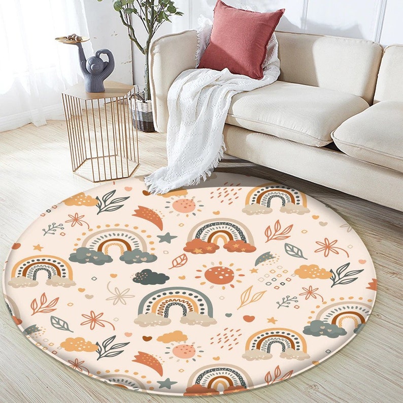 May include: A round rug with a white background and a repeating pattern of rainbows, clouds, stars, suns, and leaves in shades of orange, brown, green, and gray.