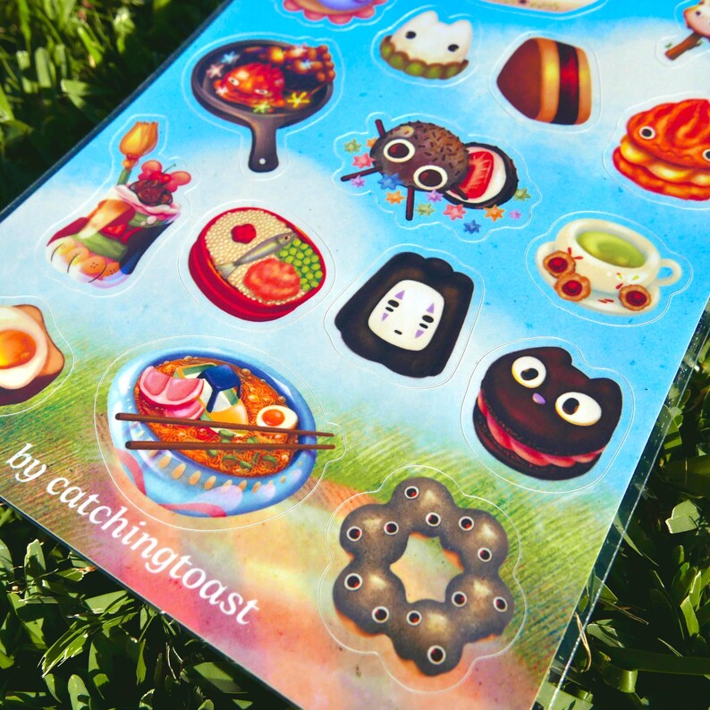 Puede incluir: Una hoja de pegatinas coloridas con ilustraciones de comida y dise&ntilde;os de personajes. Las pegatinas incluyen im&aacute;genes de ramen, sushi, panqueques y una galleta con forma de gato. El texto "by catchingtoast" es visible en la parte inferior izquierda.