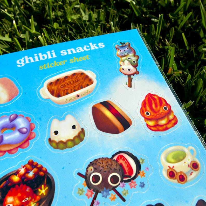Puede incluir: Una hoja de pegatinas con varias ilustraciones coloridas de snacks Ghibli. La hoja presenta im&aacute;genes de un plato horneado, un donut, un s&aacute;ndwich, una pila de golosinas naranjas y otros alimentos. El texto "Ghibli snacks sticker sheet" est&aacute; impreso en la parte superior.