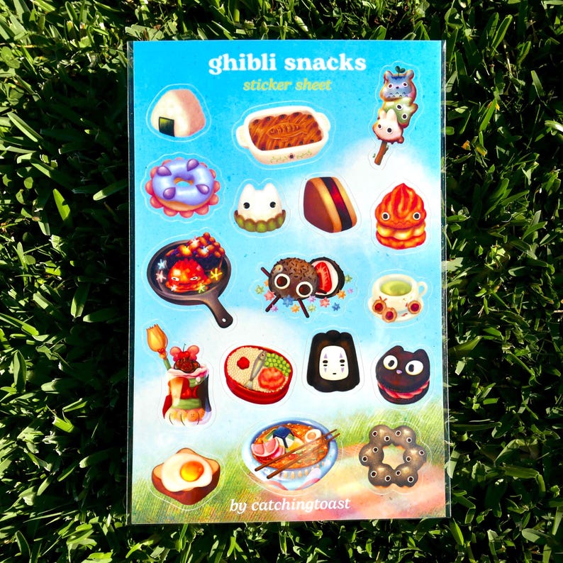 Puede incluir: Una hoja de pegatinas titulada "Ghibli snacks" con ilustraciones coloridas de varios alimentos. La hoja incluye im&aacute;genes de onigiri, donuts y otros aperitivos. El texto "by catchingtoast" est&aacute; en la parte inferior.