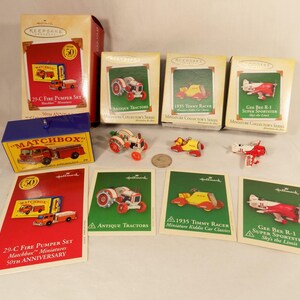 May include: A collection of Hallmark miniature vehicles, including a fire pumper set, antique tractors, a 1935 Timmy Racer, and a Gee Bee R-1 Super Sportster. The set includes boxes and cards with the Hallmark logo and product details.