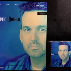May include: A blue and white sheet music book with the title "Wayne Watson" and the text "Piano, Guitar, Vocal" at the top. The cover features a photo of Wayne Watson, a man with short brown hair and a blue shirt. The book is for medium voice range.
