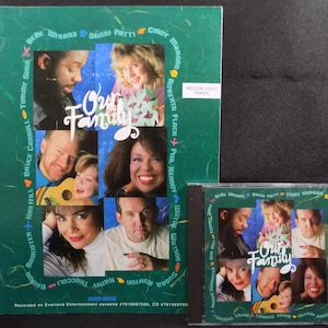 May include: A green and white cassette tape case with a photo of a group of people on the front. The case is titled "Our Family" and includes the names of the singers on the tape. The text "Medium Voice Range" is also included on the case.