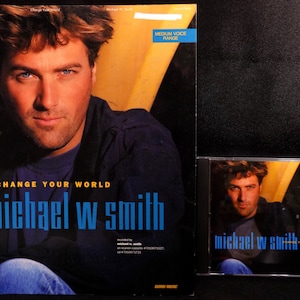 May include: A CD and sheet music for the song "Change Your World" by Michael W. Smith. The cover features a photo of Michael W. Smith with a blue shirt and blue jeans.